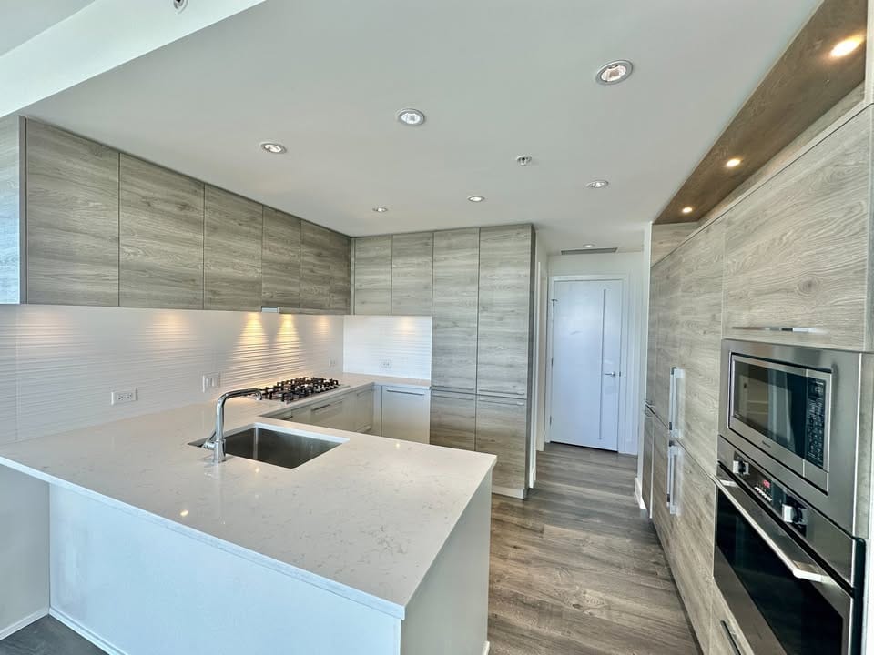Contemporary kitchen design featuring minimalist cabinetry, a spacious island, and high-end appliances at 1910-7458 Edmonds St., Burnaby.