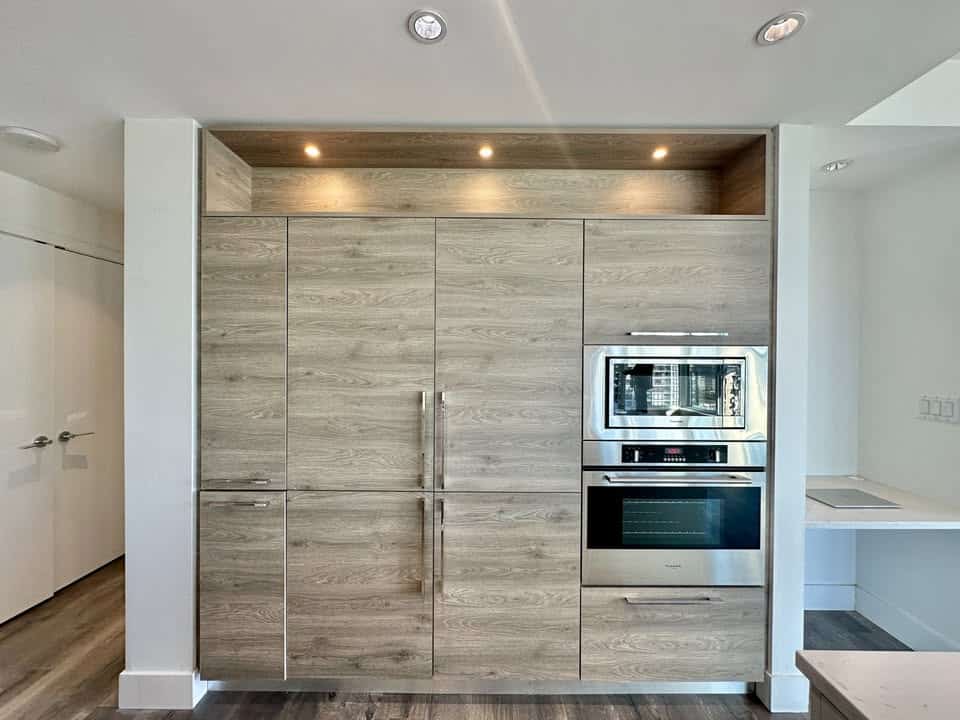 Spacious kitchen with sleek, wood-finish cabinets and built-in appliances, perfect for contemporary home living in Burnaby.