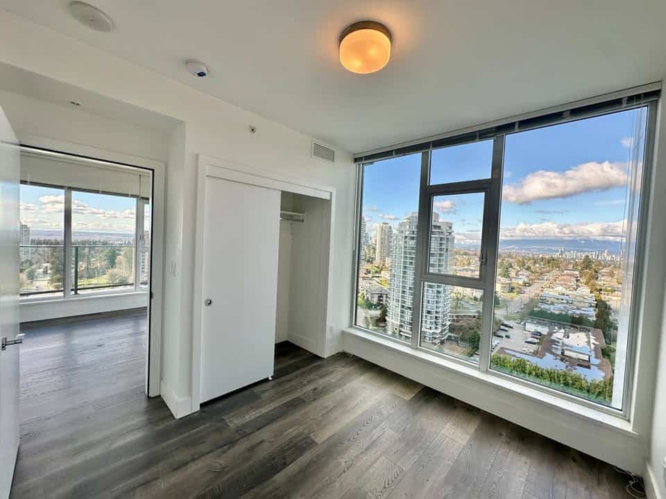 Bright, modern condo interior in Burnaby with large windows showcasing cityscape views, hardwood floors, and a spacious layout. Perfect for urban living and investment.