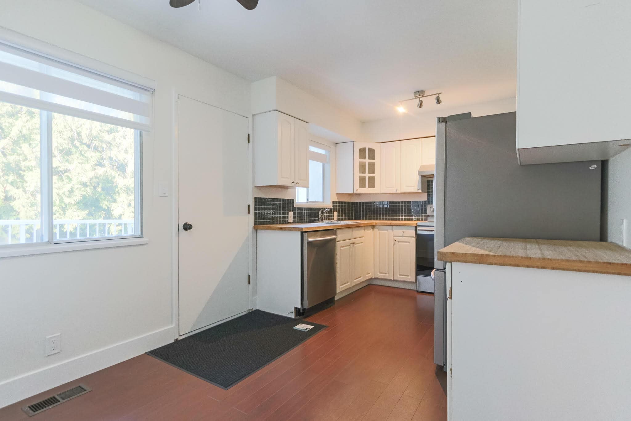 Bright and modern upstairs kitchen in Delta with white cabinetry and stainless steel appliances.