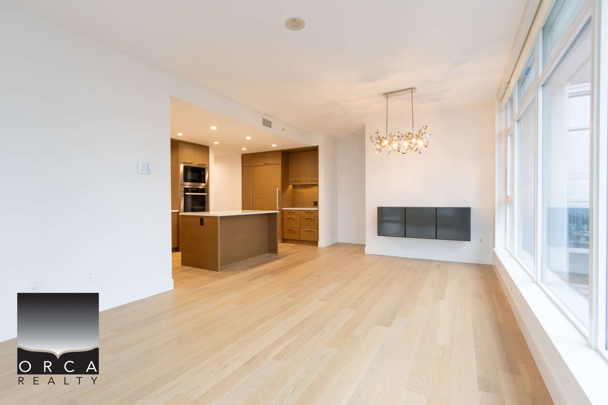 Spacious living area in a Vancouver condo at 1106-4360 Beresford Street, featuring hardwood floors, contemporary lighting, and abundant natural light from floor-to-ceiling windows.