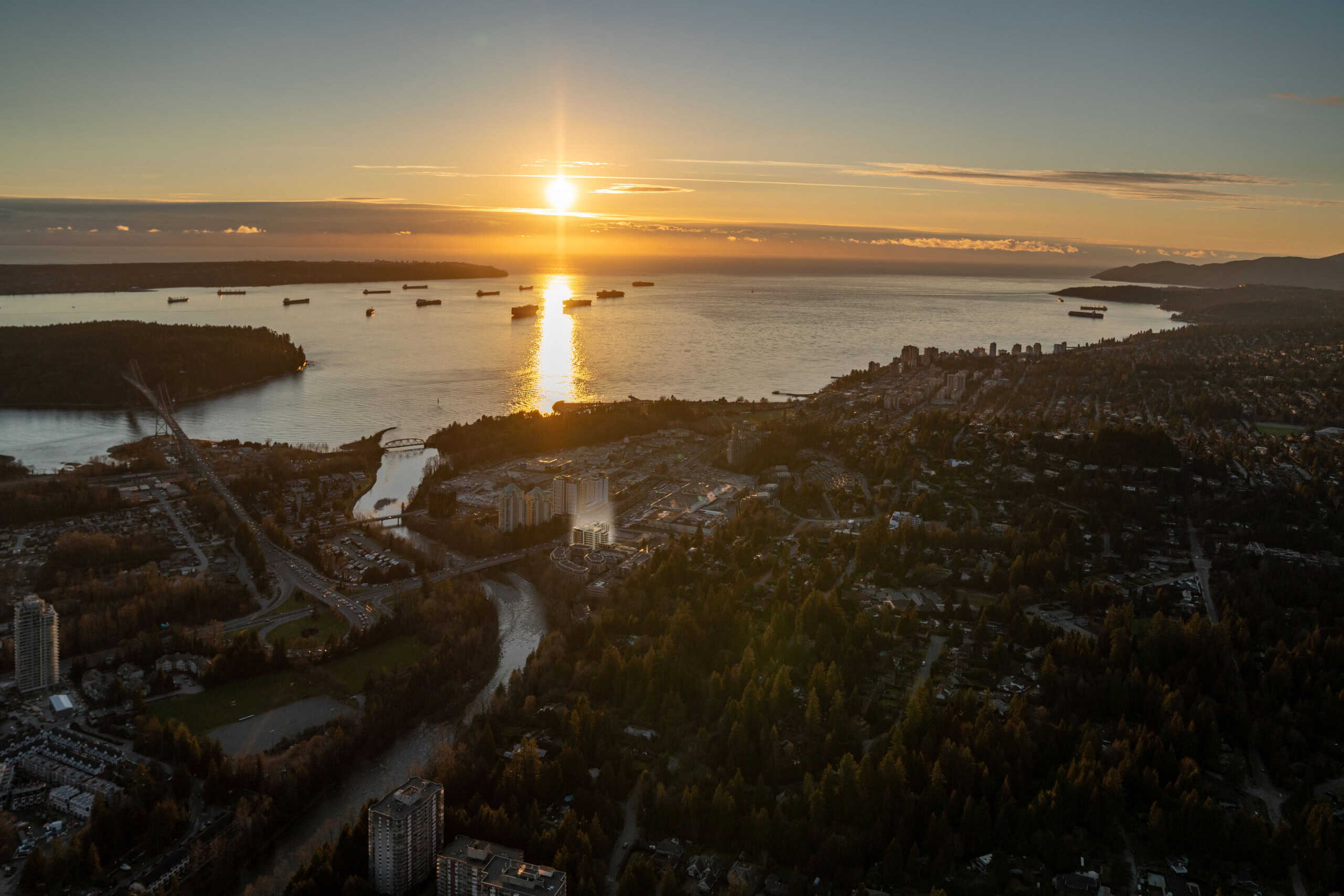 Aerial view of West Vancouver at sunset, showcasing the beautiful waterfront, lush greenery, and residential neighborhoods near 702-423 6th Street. Perfect for real estate and property listings.