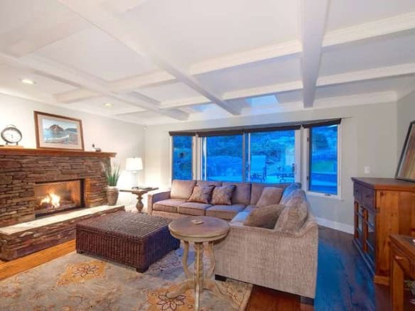 Spacious living room in a West Vancouver home with a cozy fireplace, large windows, and elegant decor, perfect for relaxing and entertaining.