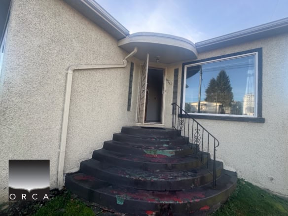 Vancouver real estate listing at 4711 Victoria Drive showcasing a charming home with a curved front porch, large window, and well-maintained exterior, ideal for potential buyers.