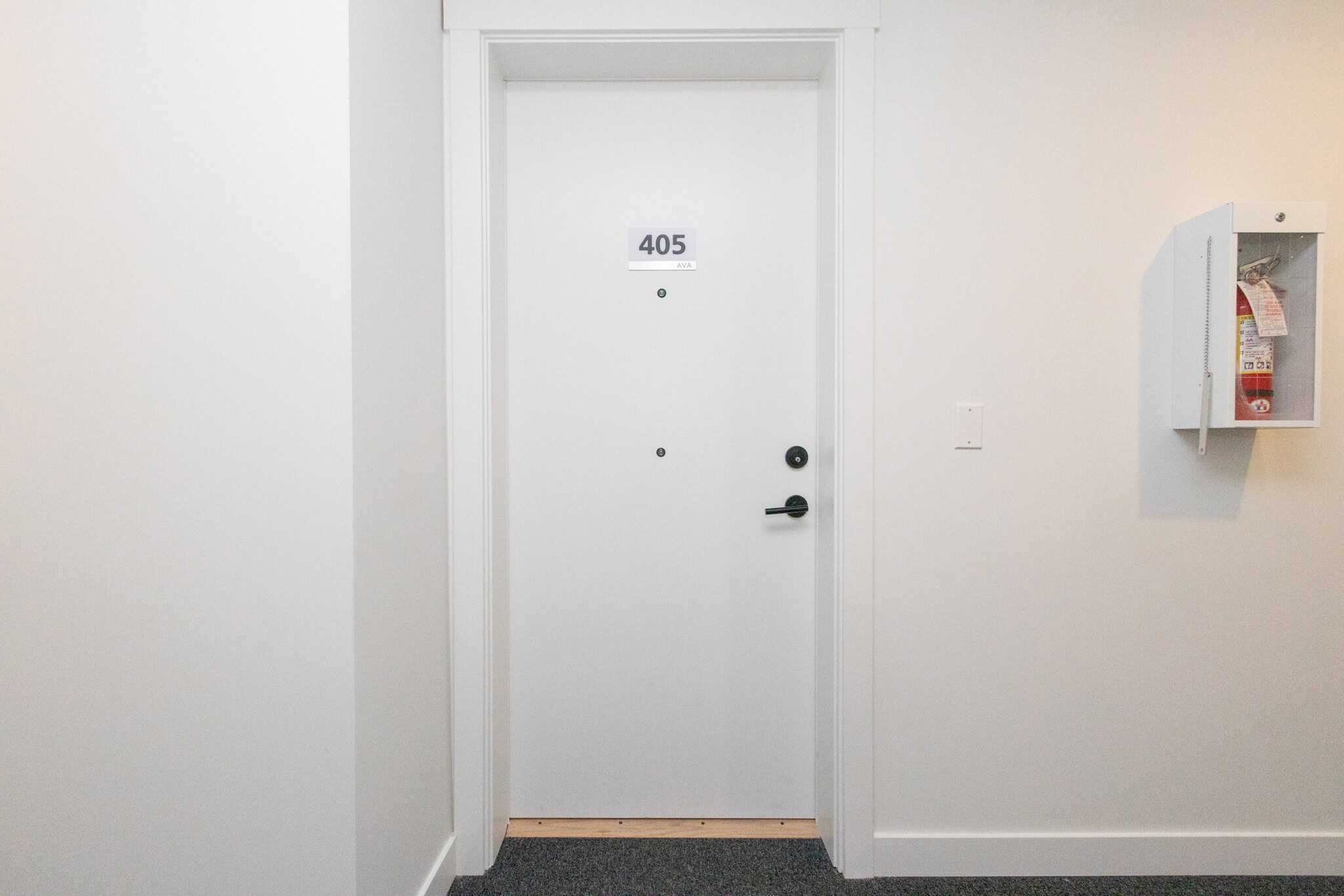 Bright white door with unit number 405, in a clean, well-maintained hallway.