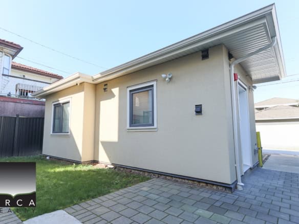 Contemporary single-story house in Vancouver with beige stucco exterior, small windows, and a paved driveway, located at 3-3545 East 26th Avenue.