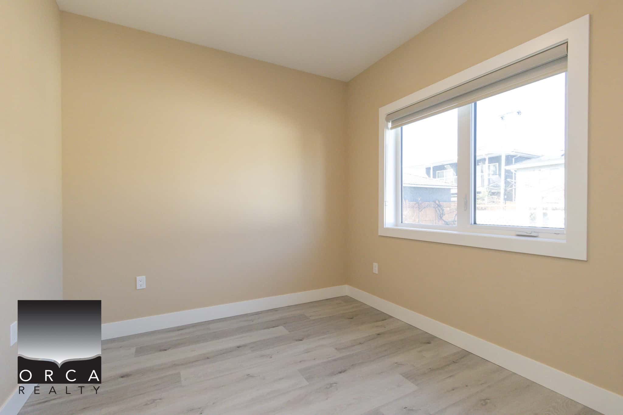 Bright, empty room with beige walls and large window in Vancouver property.