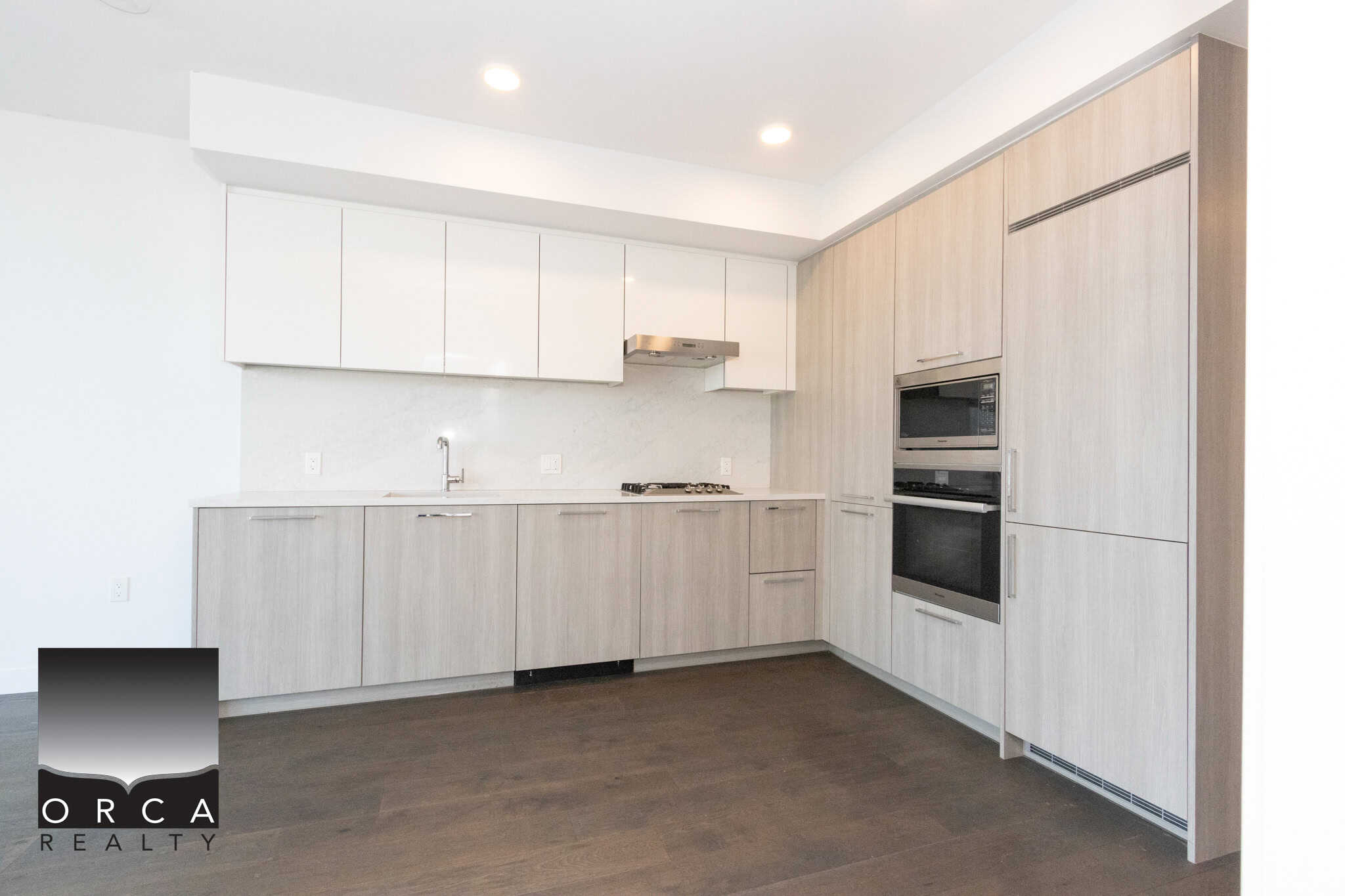 Modern kitchen with light wood cabinets and stainless steel appliances. Spacious kitchen featuring sleek light wood cabinetry, built-in oven, and modern design, perfect for Richmond homeowners seeking contemporary real estate options.