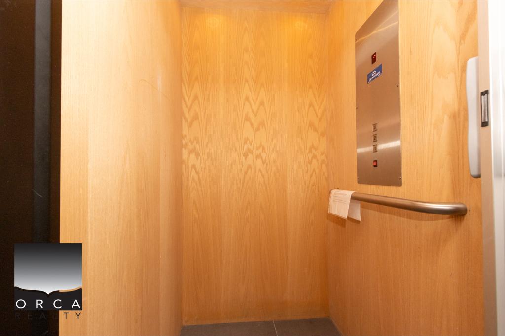 Elevator interior with wooden paneling and stainless steel handrail at Ansell Place, showcasing contemporary residential building amenities.