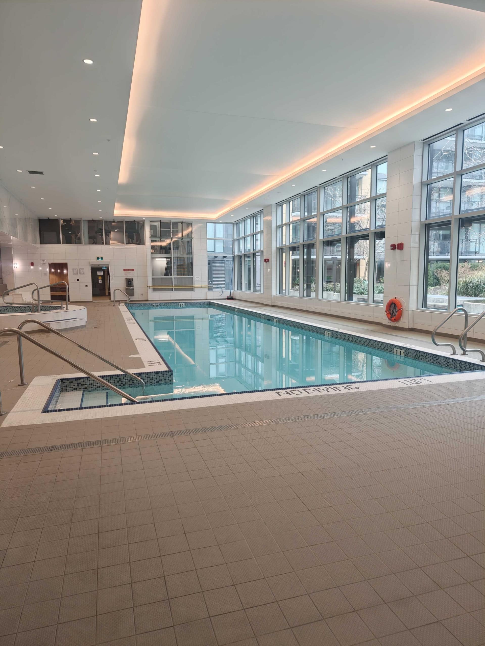 Modern indoor swimming pool at 702E-3280 Corvee Way, Richmond, featuring large windows and contemporary design. Indoor swimming pool with large windows, natural light, and modern amenities at 702E-3280 Corvee Way, Richmond. Perfect for relaxation and fitness in a luxurious residential setting.