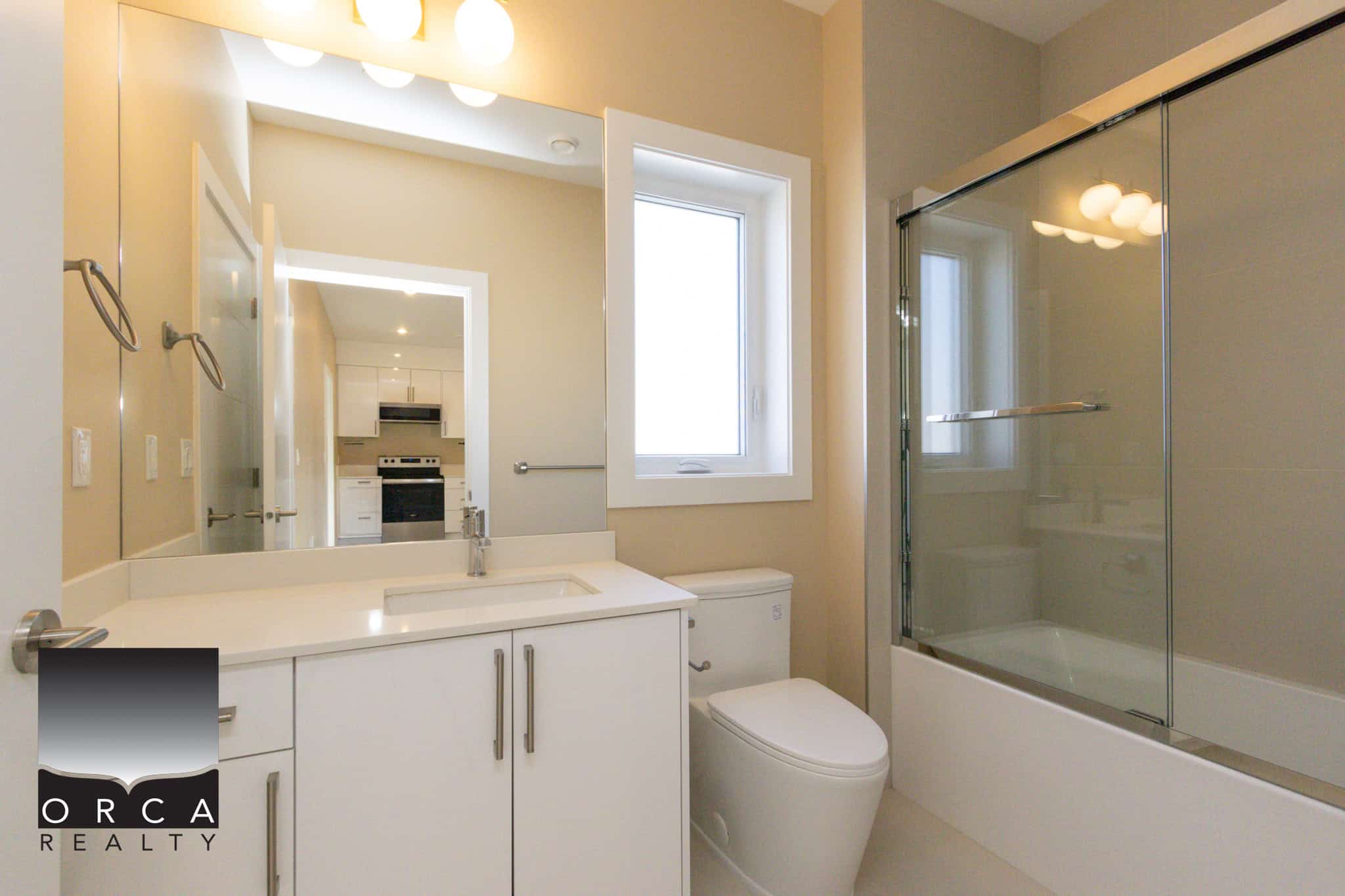 Bright Vancouver bathroom featuring a glass-enclosed shower, white vanity, and natural light from a window, ideal for contemporary home living.