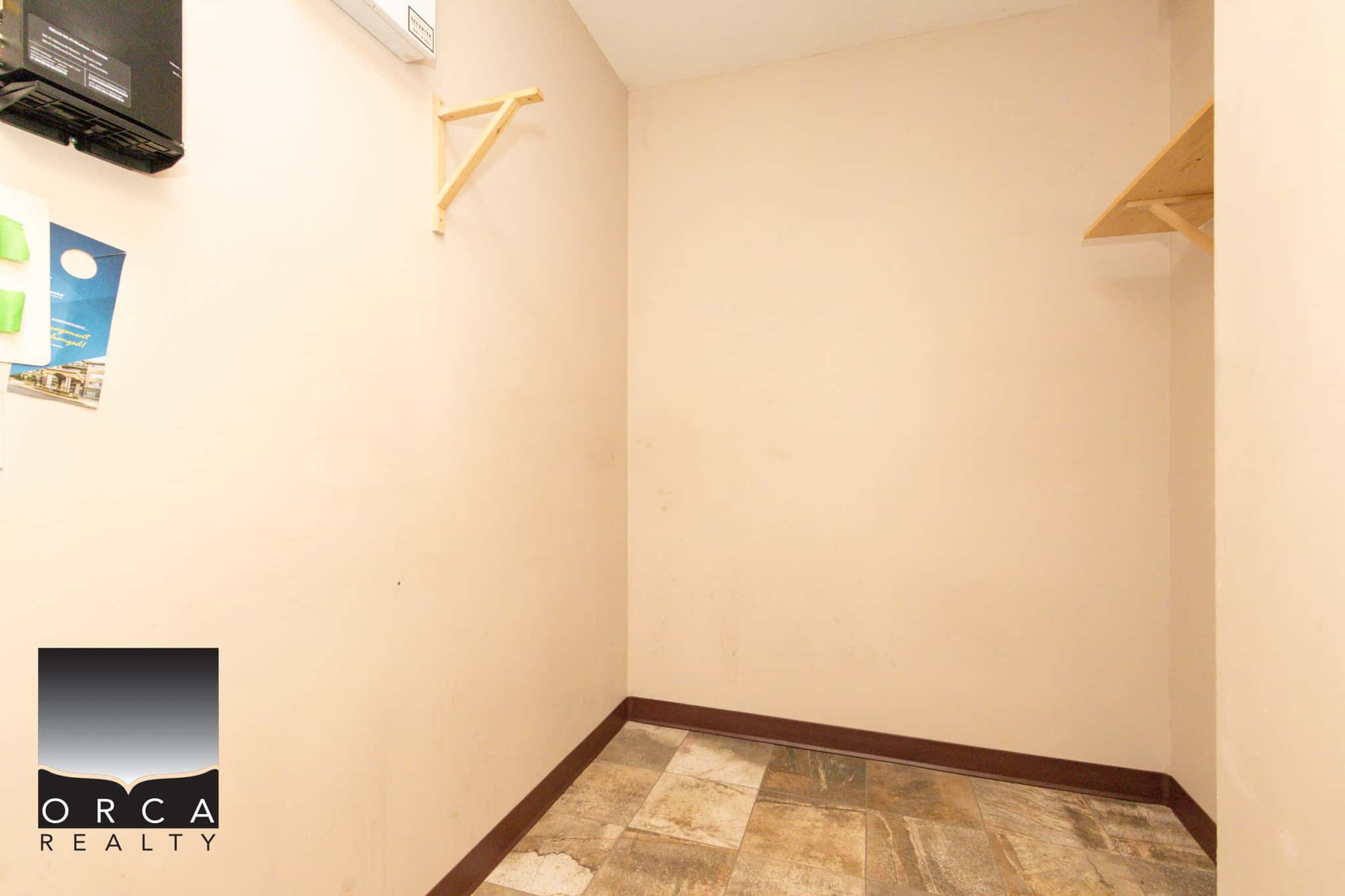 Coquitlam real estate interior view at 202-1185 Pacific St, showcasing a clean, minimalist space with neutral walls and tiled flooring, ideal for potential buyers.