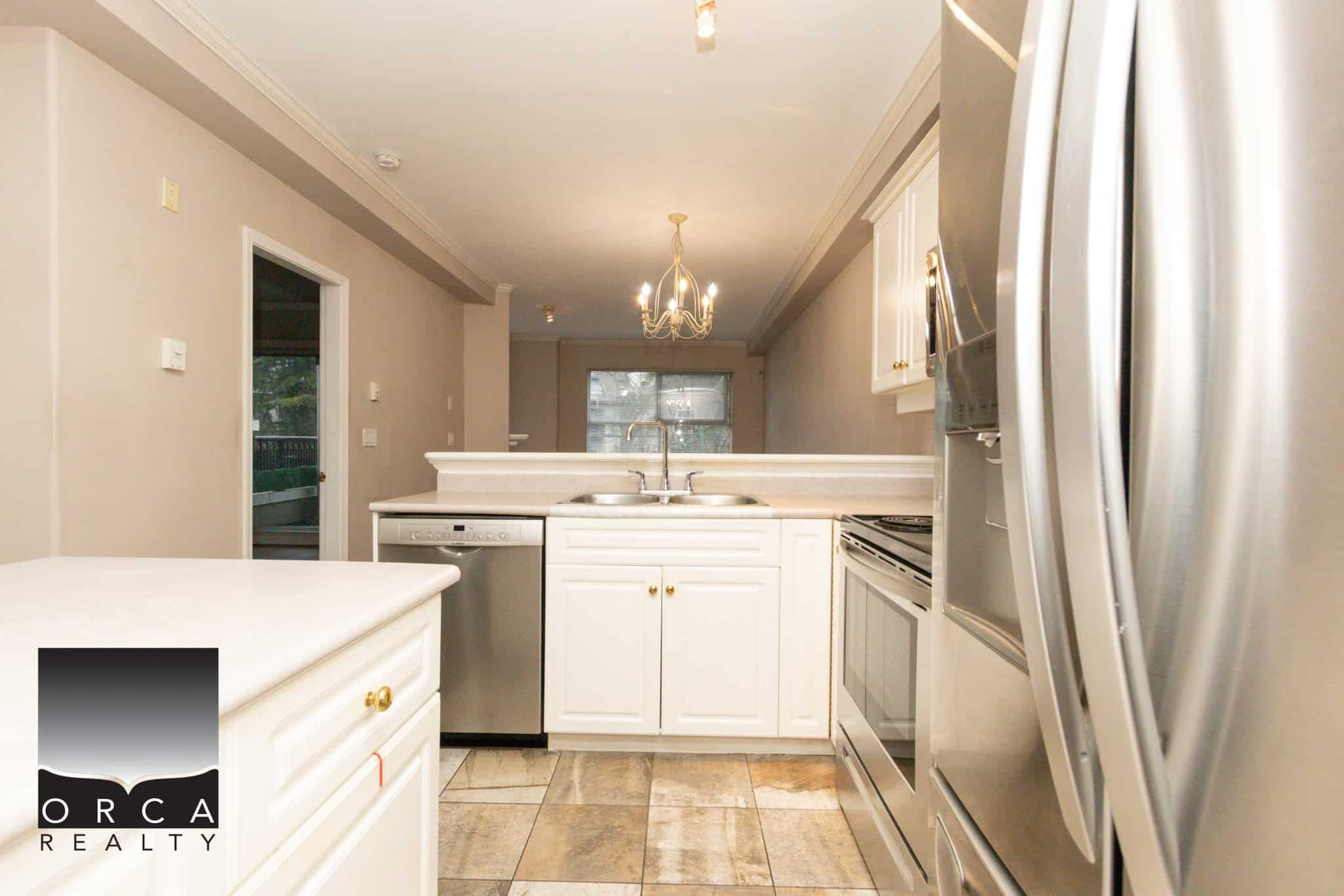 Spacious kitchen in Coquitlam featuring stainless steel appliances, white cabinets, and ample counter space, perfect for family living and entertaining.