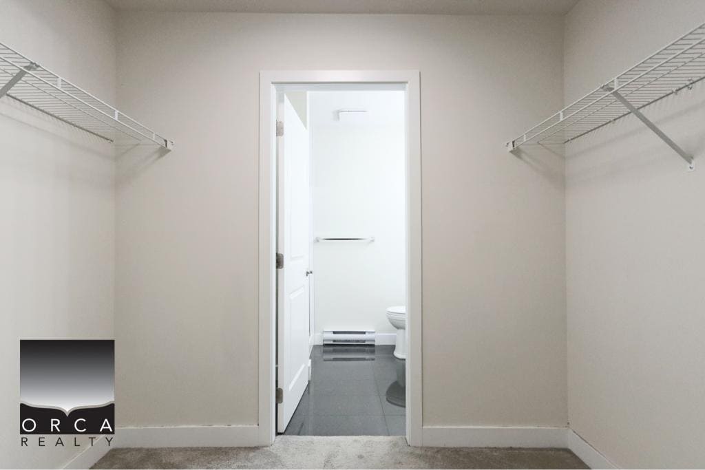 Spacious walk-in closet with white wire shelving, perfect for organizing clothing and accessories in a contemporary Surrey condo.