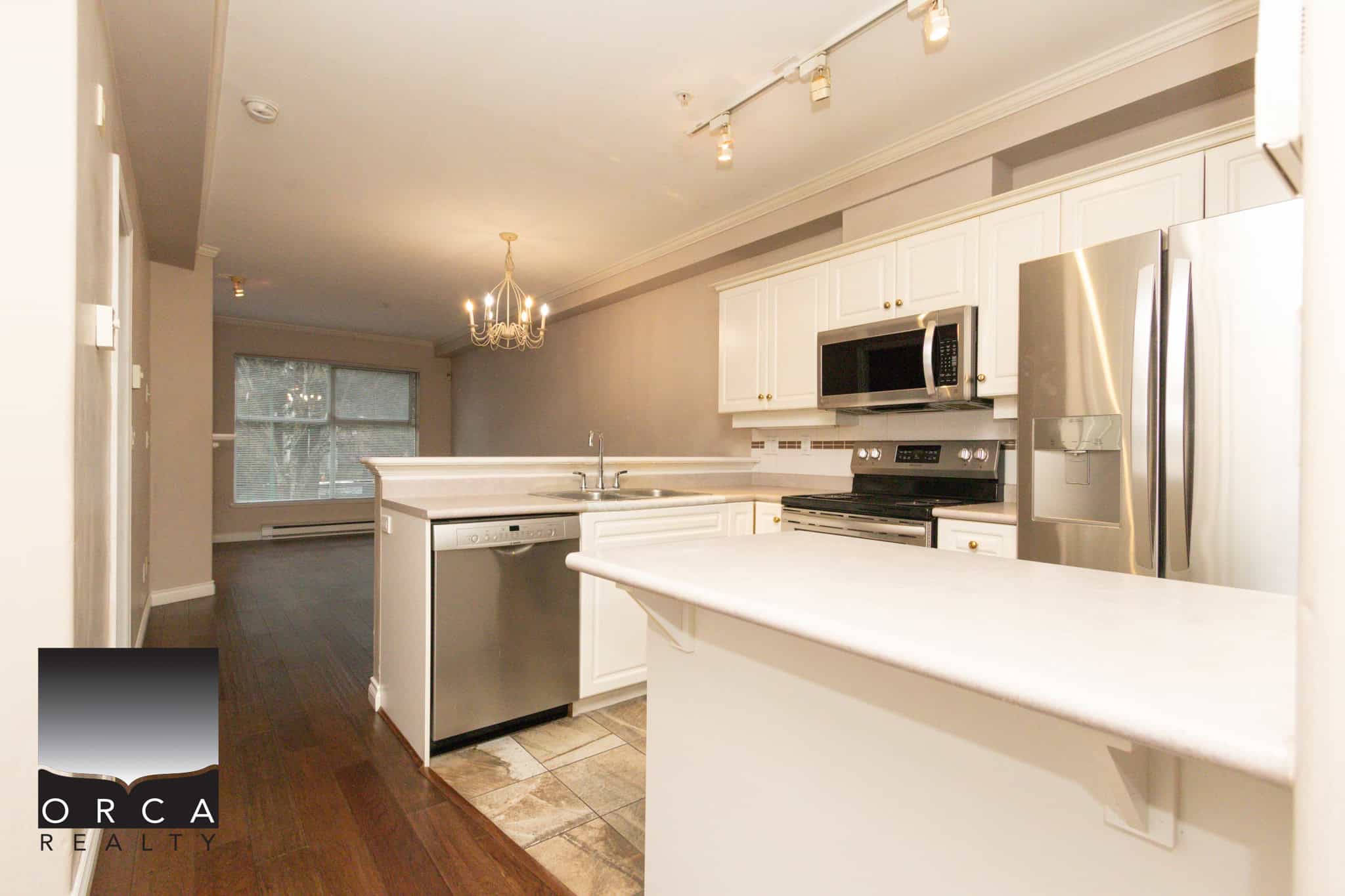 Bright and modern kitchen in Coquitlam featuring white cabinetry, stainless steel appliances, and a spacious layout, perfect for family living and entertaining.