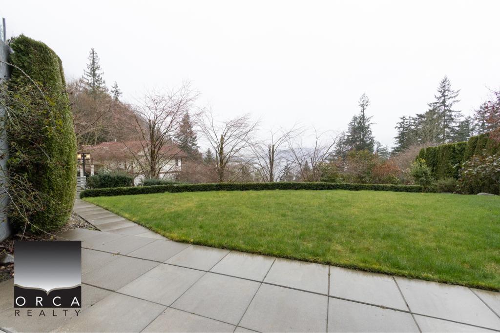 Spacious backyard with well-maintained lawn, paved patio, and surrounding greenery, perfect for outdoor living and entertaining in the Ansell Place neighborhood.