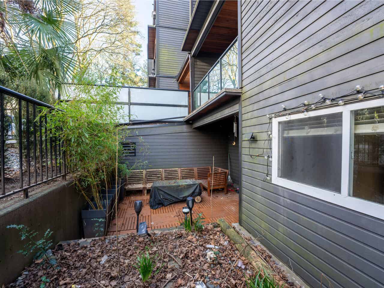 Outdoor patio area of a Vancouver townhouse featuring a wooden deck, garden plants, and modern exterior siding, ideal for relaxing or entertaining guests.