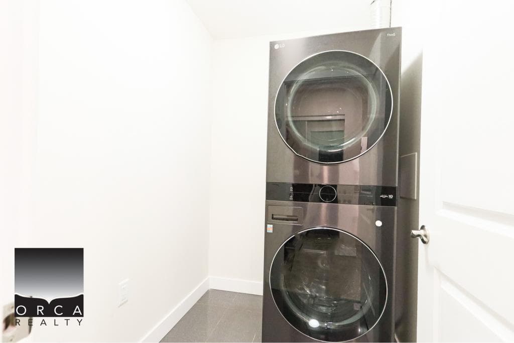 Modern front-loading washer and dryer in a bright laundry room in Surrey, BC. Perfect for convenient home living near 410-15895 84th Ave.