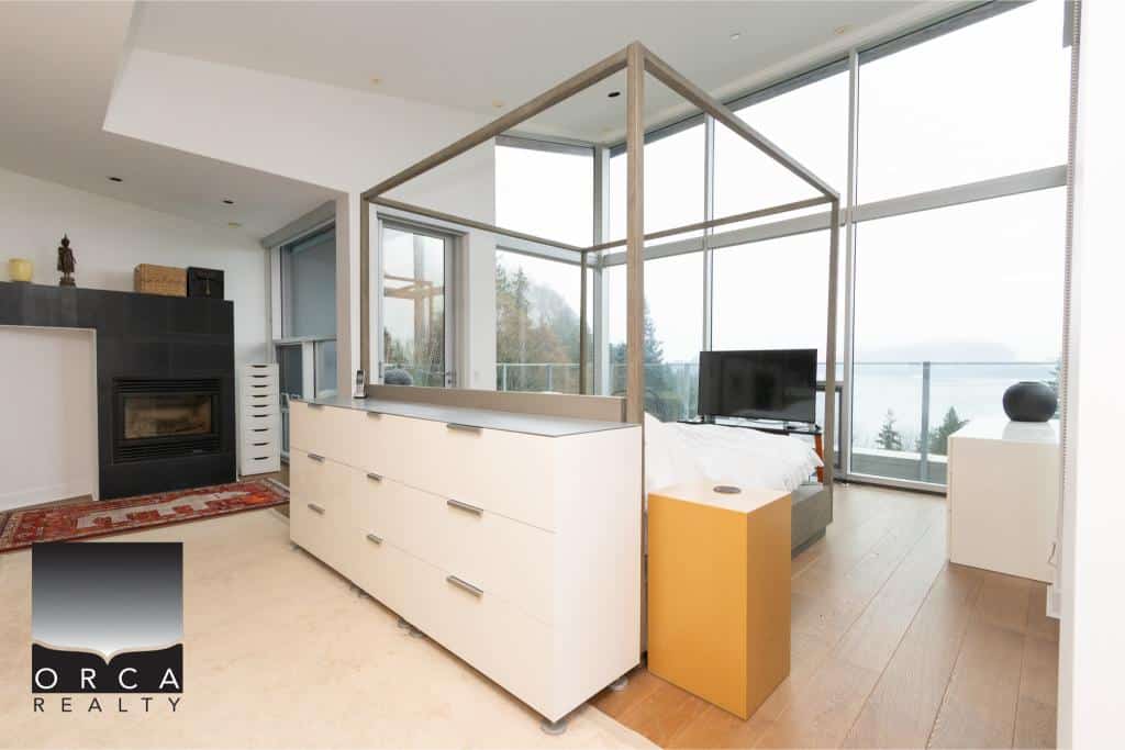 Bright, contemporary living space featuring expansive windows offering stunning views, a sleek fireplace, and stylish furnishings in a luxurious Ansell Place residence.