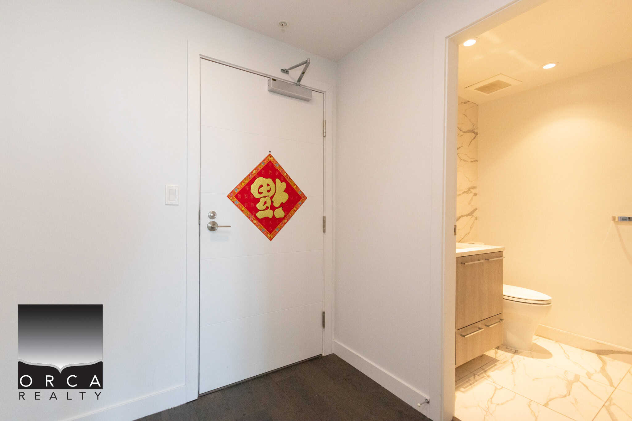 Modern Richmond condo bathroom with white walls and marble flooring. Bright and clean interior featuring a bathroom with a toilet, vanity, and marble accents, perfect for comfortable living in Richmond.