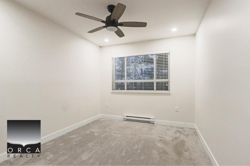 Bright and spacious Surrey condo room featuring a ceiling fan, large window with blinds, neutral walls, and plush carpet, ideal for comfortable living and modern home design.