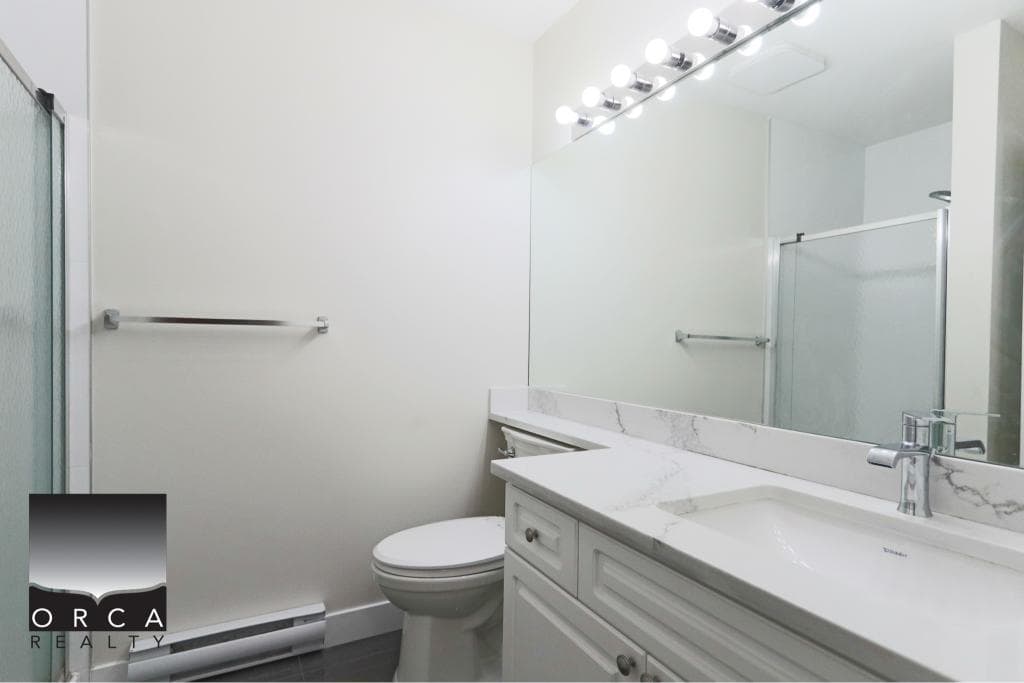 Bright and clean bathroom featuring a sleek vanity, large mirror, and contemporary lighting, perfect for a comfortable home in Surrey.