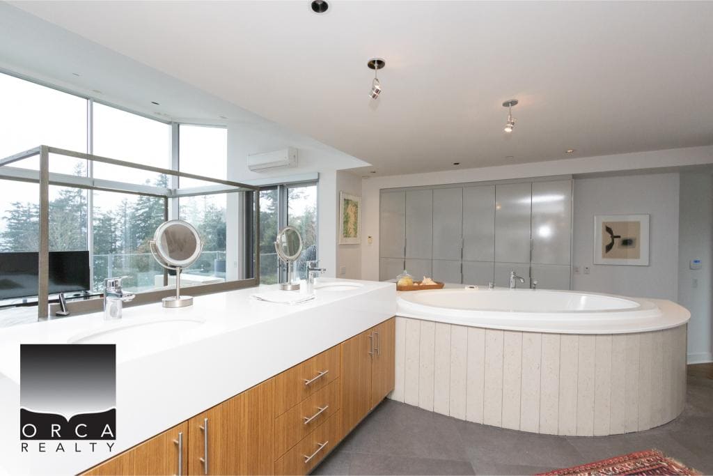 Spacious Ansell Place bathroom featuring a large whirlpool tub, modern fixtures, and expansive windows offering natural light and scenic views. Perfect for relaxing in a luxurious setting.