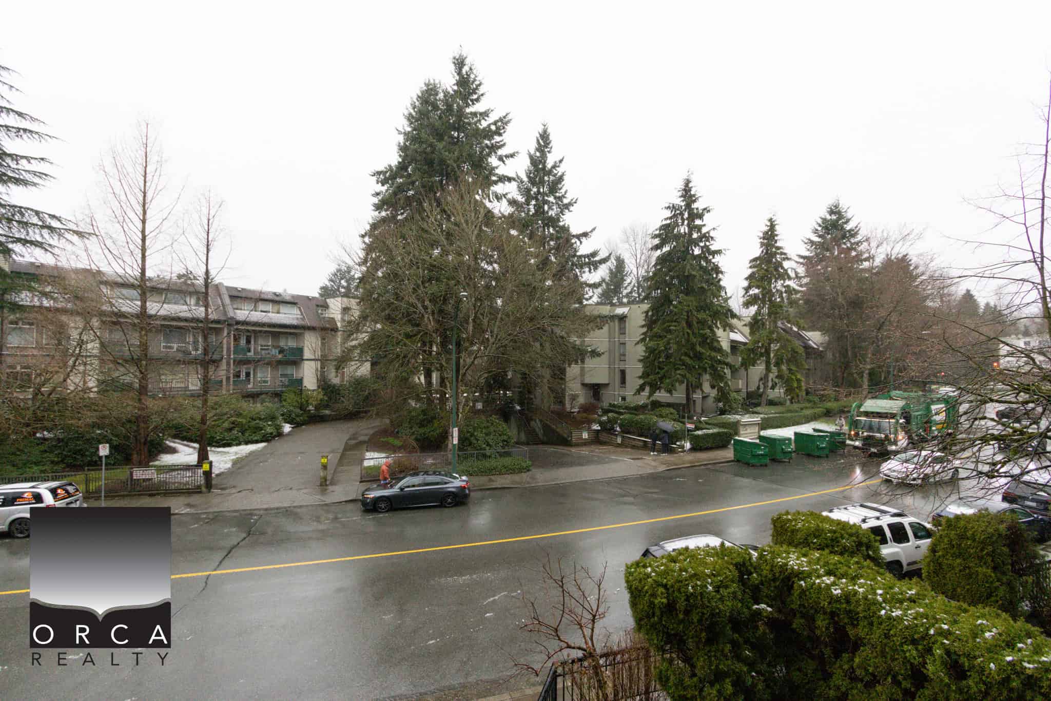 Spacious residential street view in Coquitlam, BC, showcasing lush trees and apartment buildings, ideal for real estate listings and property marketing.