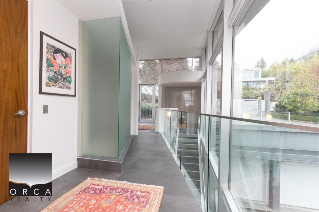 Bright, airy corridor with large windows and glass railing, showcasing contemporary interior design.
