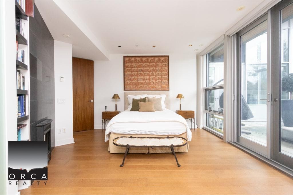 Spacious bedroom featuring large windows, wooden flooring, and contemporary decor at Ansell Place, offered by Orca Realty Inc.