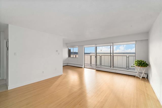 Bright, open-concept living room with large windows and ocean views in West Vancouver. Modern interior with hardwood floors, ideal for luxury real estate buyers.