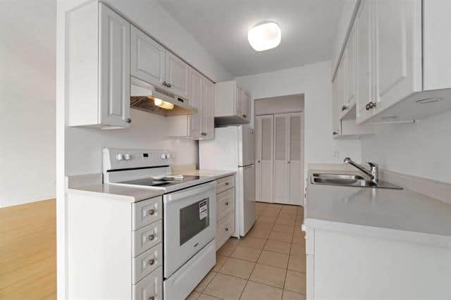 Bright kitchen with white cabinets and modern appliances in West Vancouver home.