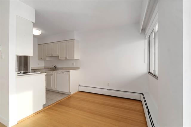 Bright interior of a West Vancouver apartment with white kitchen cabinets and hardwood flooring.