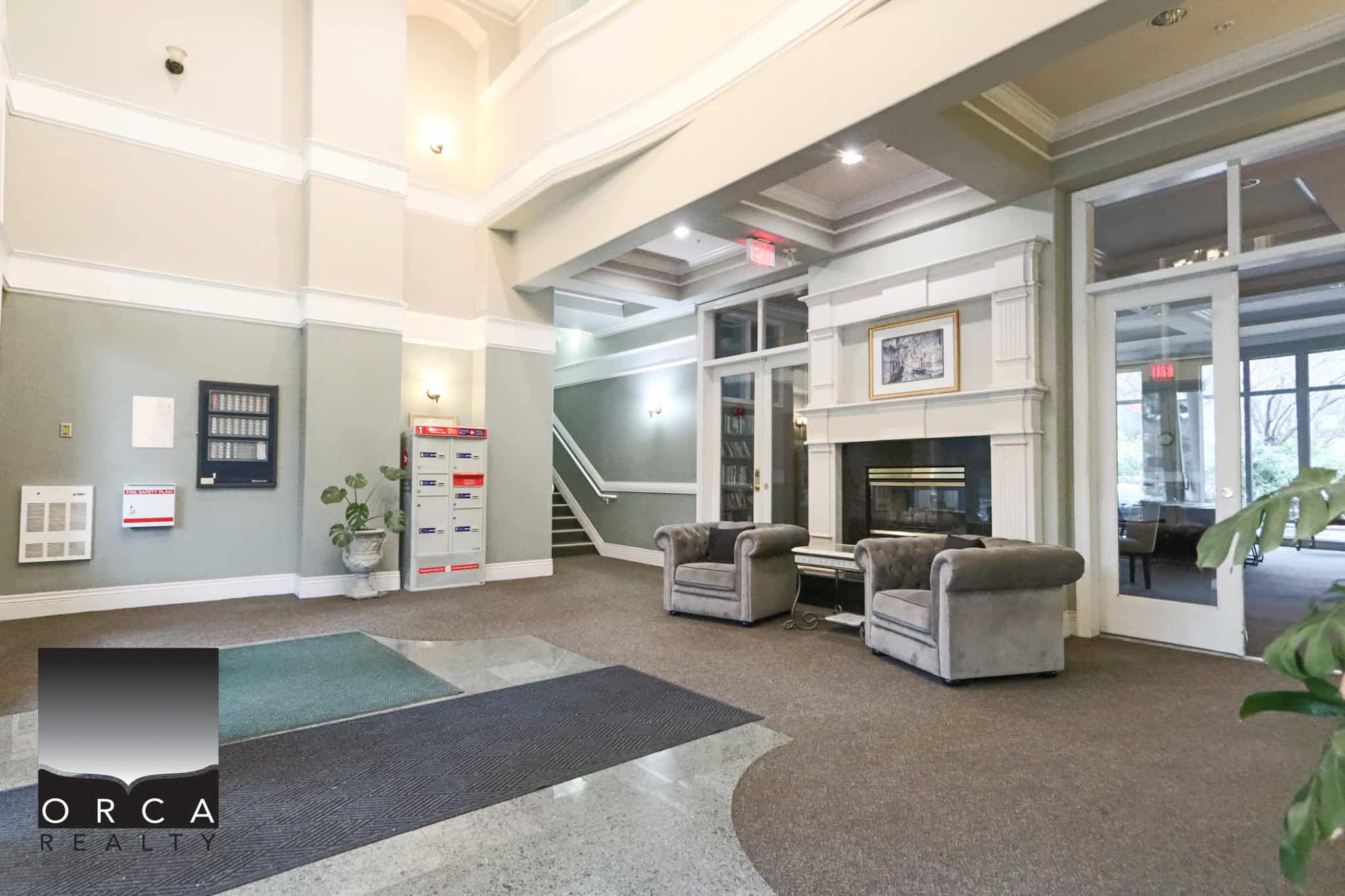 Spacious lobby of 202-1185 Pacific St, Coquitlam, featuring a cozy fireplace, comfortable seating, and contemporary decor, ideal for residents and visitors.