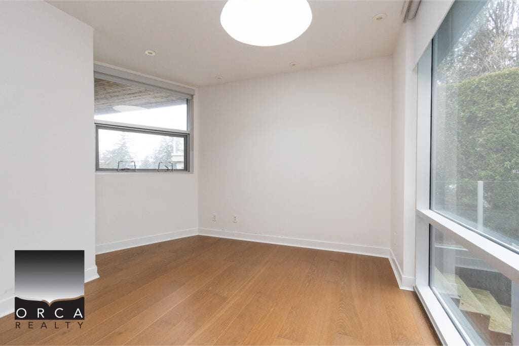 Bright and spacious living room with large windows and hardwood flooring in Ansell Place, a desirable property listed by Orca Realty Inc.