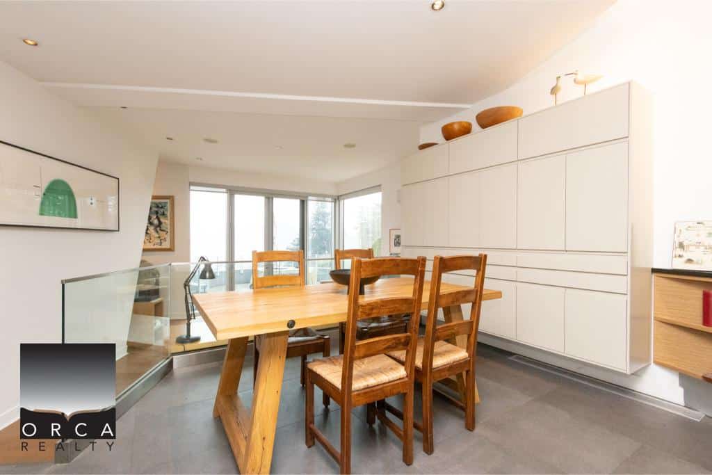 Spacious dining area with a wooden table and chairs, featuring large windows that provide natural light and scenic views, perfect for family gatherings and entertaining guests.