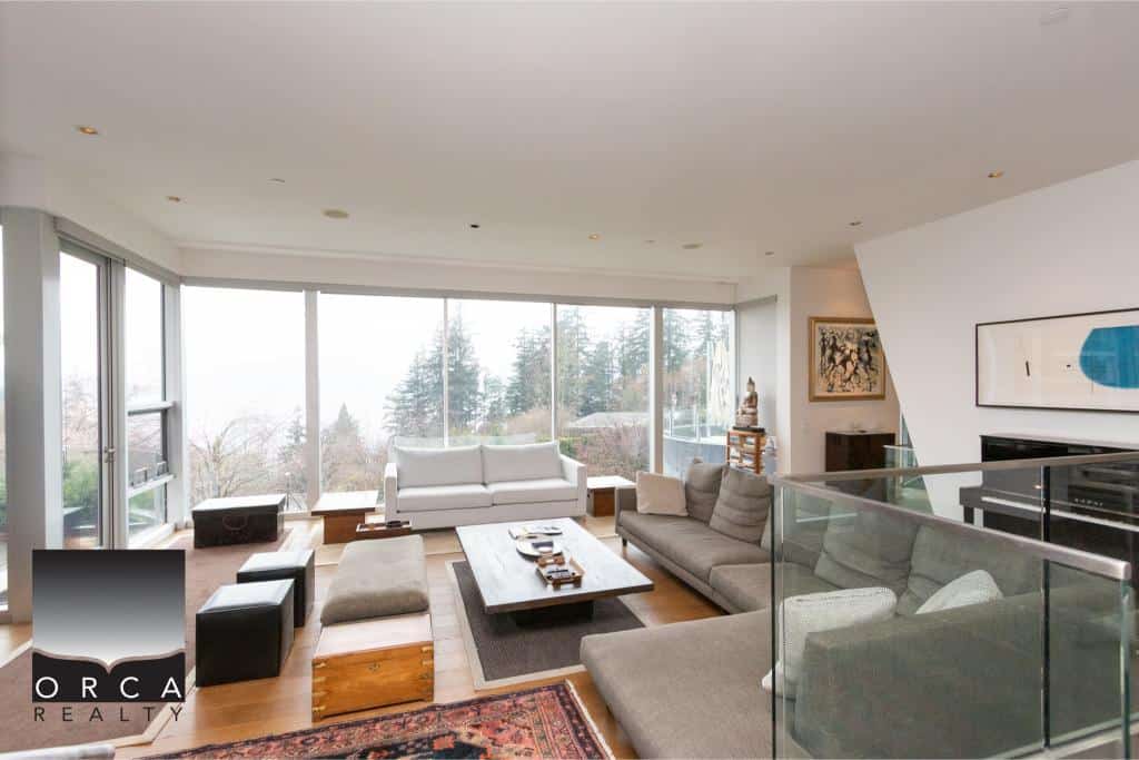 Spacious living room at Ansell Place featuring large windows, contemporary furniture, and scenic views, showcasing upscale interior design by Orca Realty Inc.
