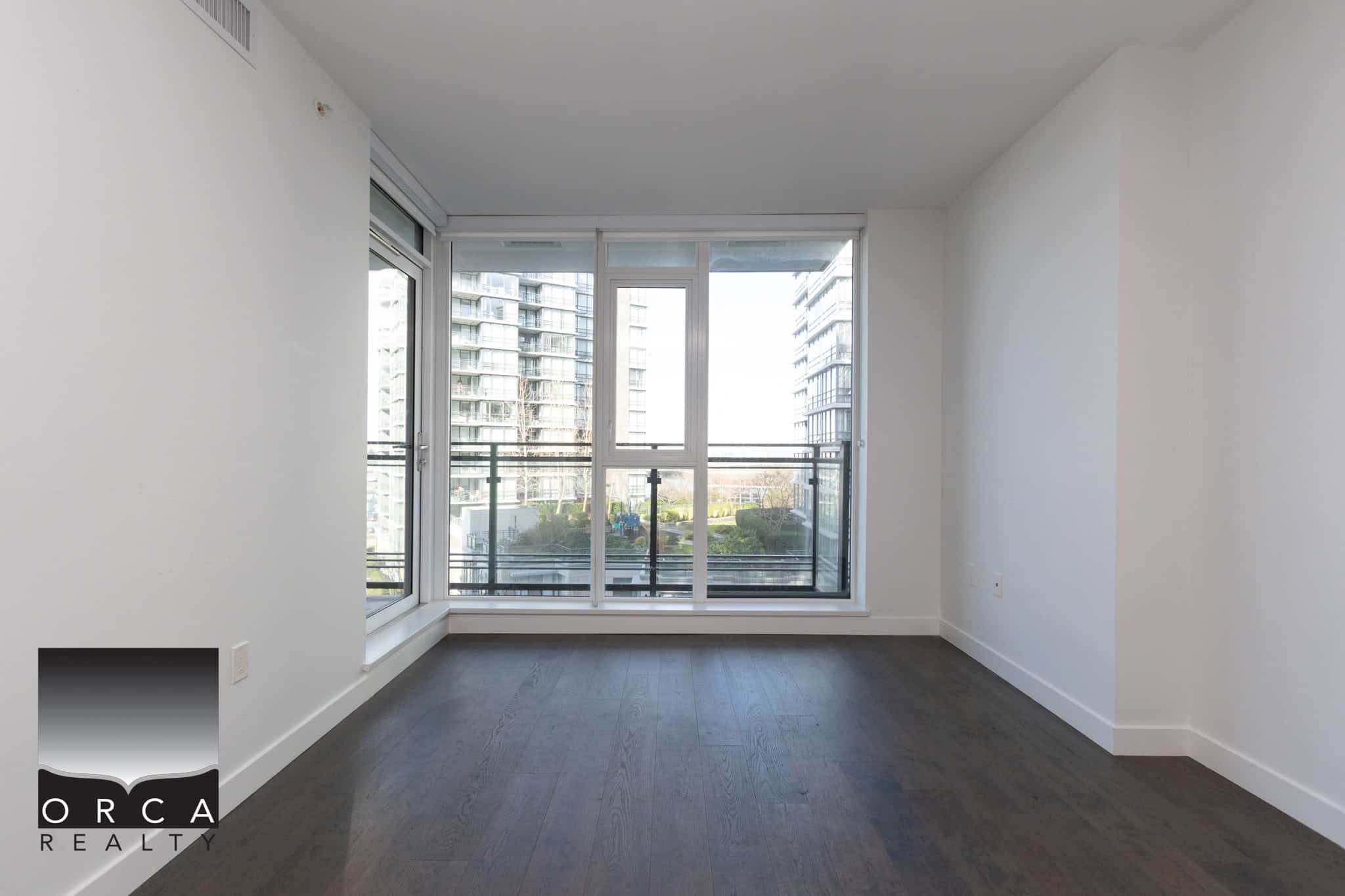 Modern apartment living room with large windows in Richmond Bright living space with expansive windows overlooking city buildings in Richmond, ideal for urban homebuyers seeking a contemporary condo near Corvee Way.