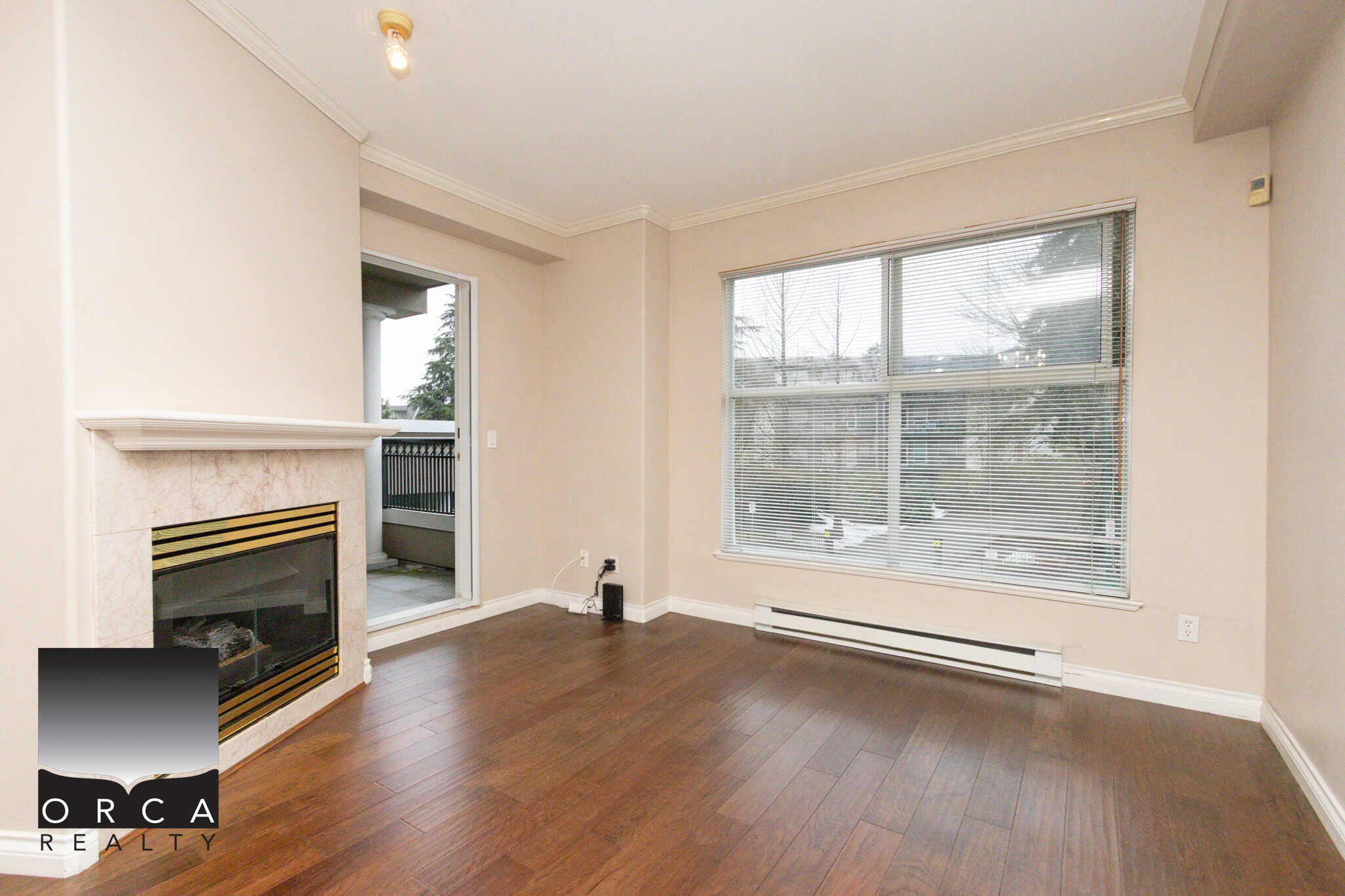 Bright living room in Coquitlam apartment with large windows and hardwood floors.