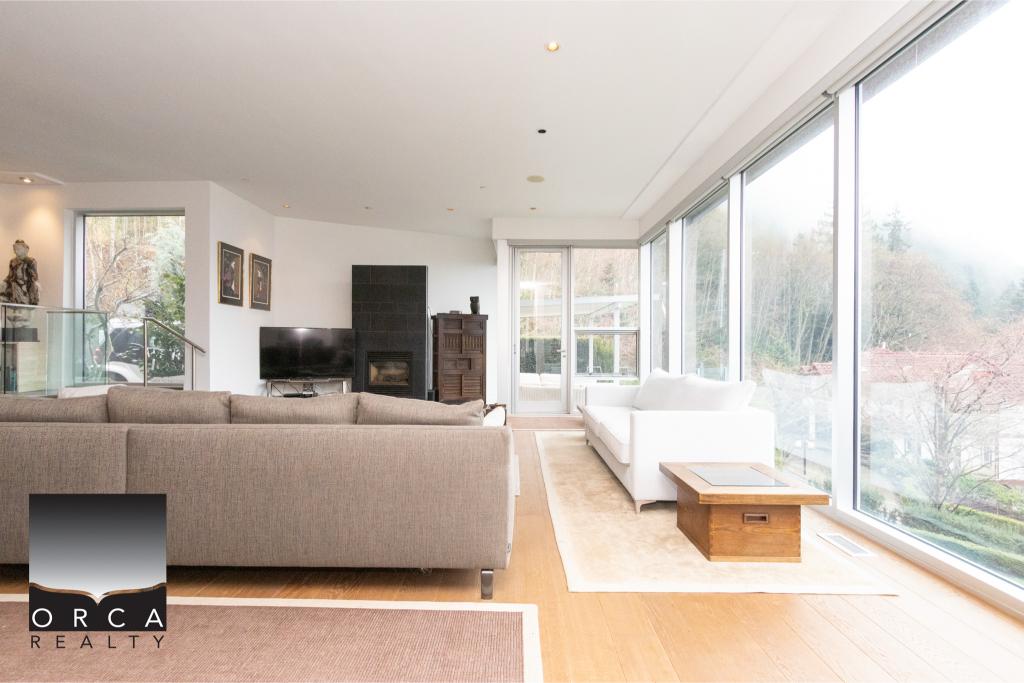 Spacious living room featuring large windows offering natural light and scenic views, with contemporary furniture and a cozy fireplace, located in Ansell Place.
