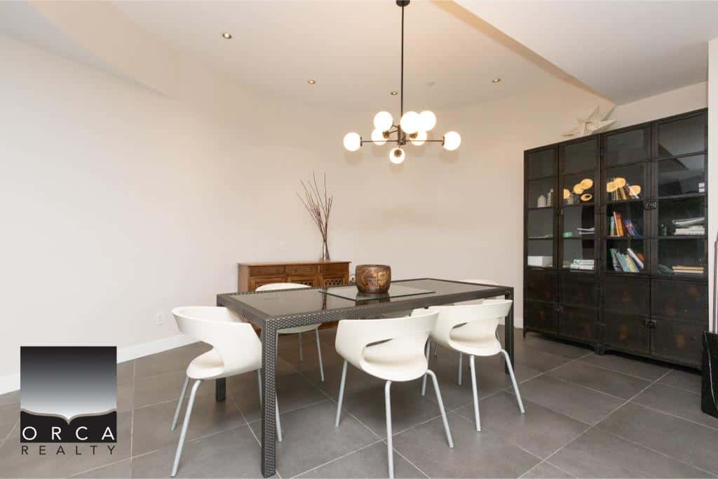 Elegant dining area with a sleek black table and white chairs, featuring contemporary decor and a stylish black bookshelf, perfect for family gatherings or entertaining guests.