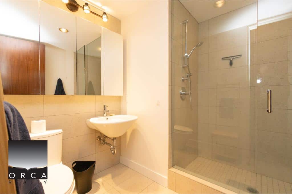 Bright, contemporary bathroom featuring a spacious walk-in shower with glass enclosure, sleek fixtures, and neutral tile finishes, perfect for comfortable living at Ansell Place.