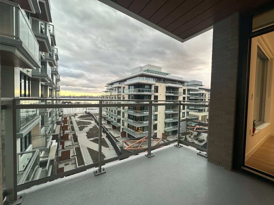 Spacious balcony overlooking North Vancouver's Harbourside Drive, offering stunning cityscape and water views, perfect for relaxing or entertaining in a contemporary condo.