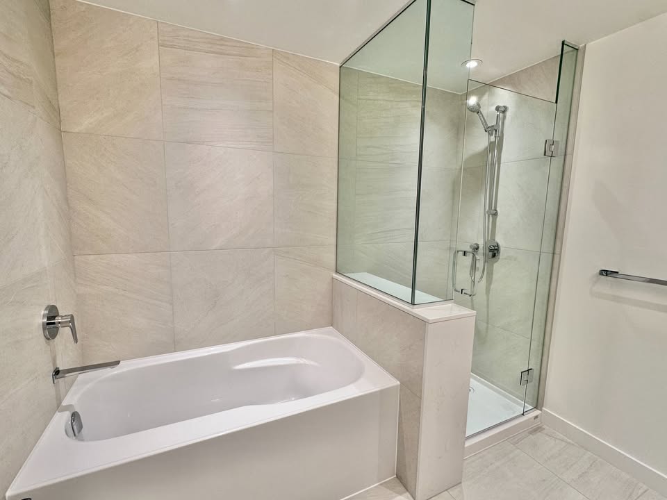 Contemporary bathroom in North Vancouver featuring a bathtub and glass-enclosed shower, perfect for luxury living at 501-755 Harbourside Drive.