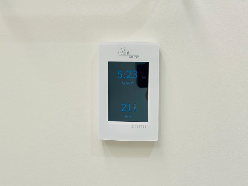 Nvent Nureva digital thermostat displaying 5:23 PM and 21.5°C, used for climate control in a residential or commercial property at 501-755 Harbourside Drive, North Vancouver.