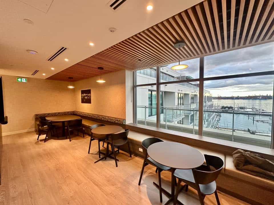 Spacious interior with large windows showcasing North Vancouver harbor views, stylish seating, and contemporary design, perfect for relaxing or meetings near 501-755 Harbourside Drive.