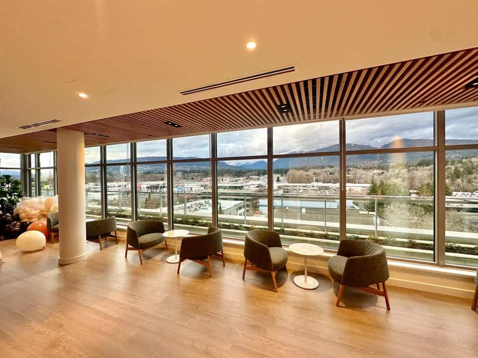 Spacious interior of a North Vancouver condo featuring comfortable seating and expansive views of the cityscape and mountains.