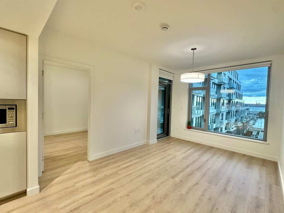 Bright and spacious living room in a North Vancouver condo with large windows, hardwood floors, and city views, perfect for urban lifestyle.