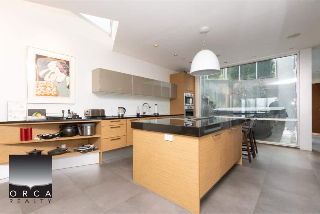 Spacious and contemporary kitchen featuring sleek cabinetry, a large island with black countertop, and ample natural light from large windows at Ansell Place. Perfect for modern living.