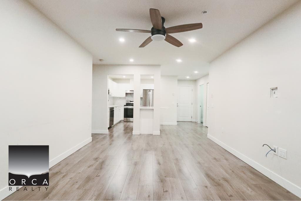 Bright open-concept living space in Surrey, BC, featuring a sleek kitchen, hardwood floors, and a ceiling fan, ideal for comfortable urban living.